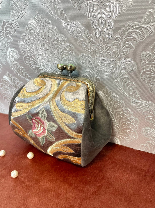 Gros plan sur le relief de la broderie et la douceur du velours gris.