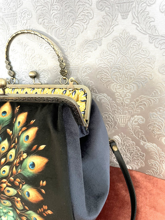 Gros plan sur le fermoir en bronze travaillé et le velours bleu nuit du sac La Plume Impériale.