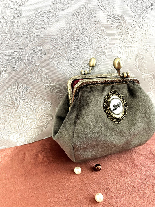 Gros plan sur le médaillon illustré d'un escarpin noir rétro et la texture soyeuse du velours vert-de-gris.