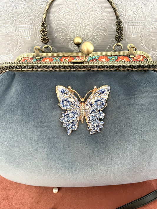 Gros plan sur l'ornement papillon au fini émaillé avec détails de fleurs bleues