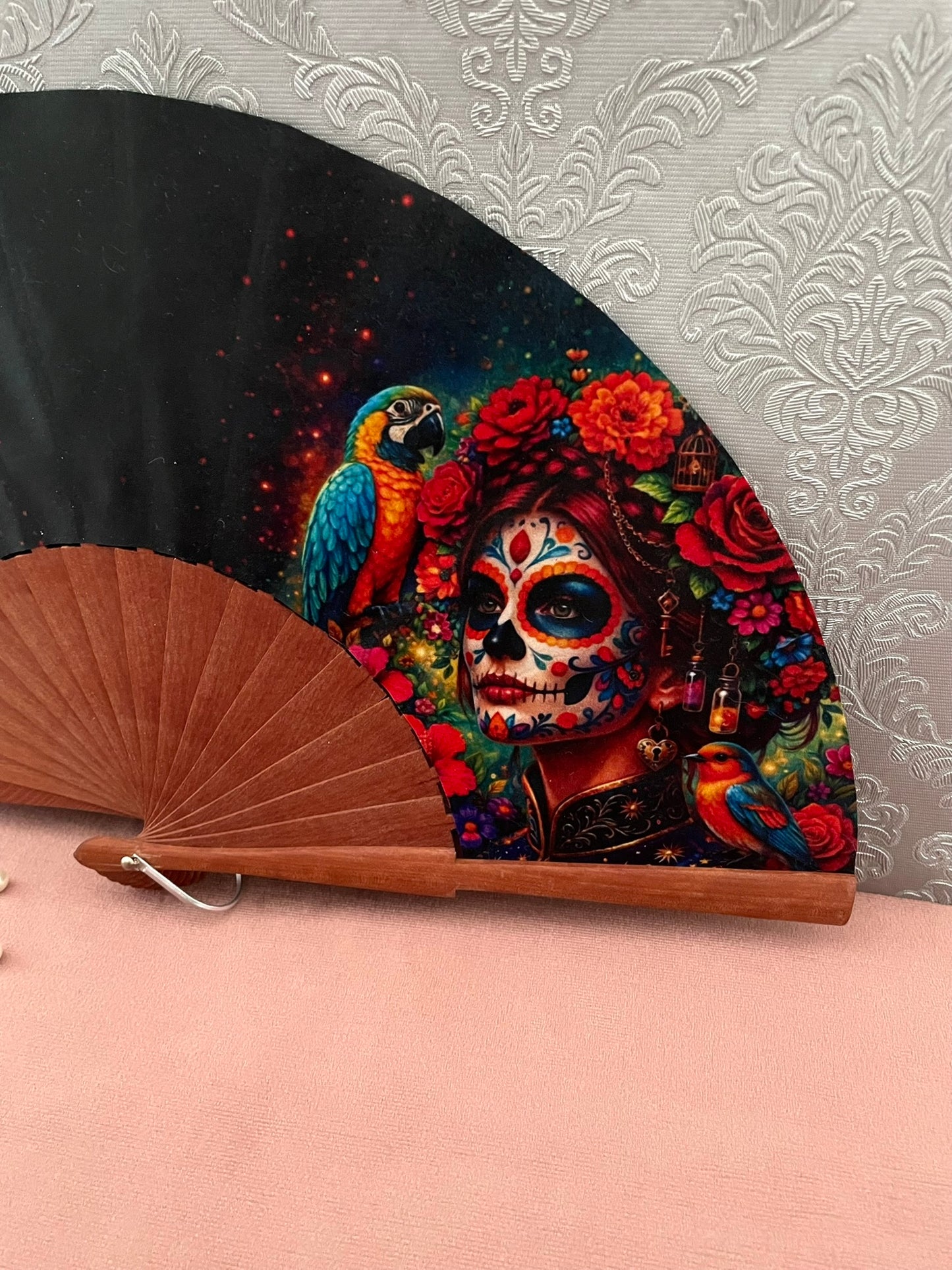 Gros plan sur le tissu exclusif au motif coloré de Calavera Catrina, fleurs de souci, roses et perroquet bleu et jaune.