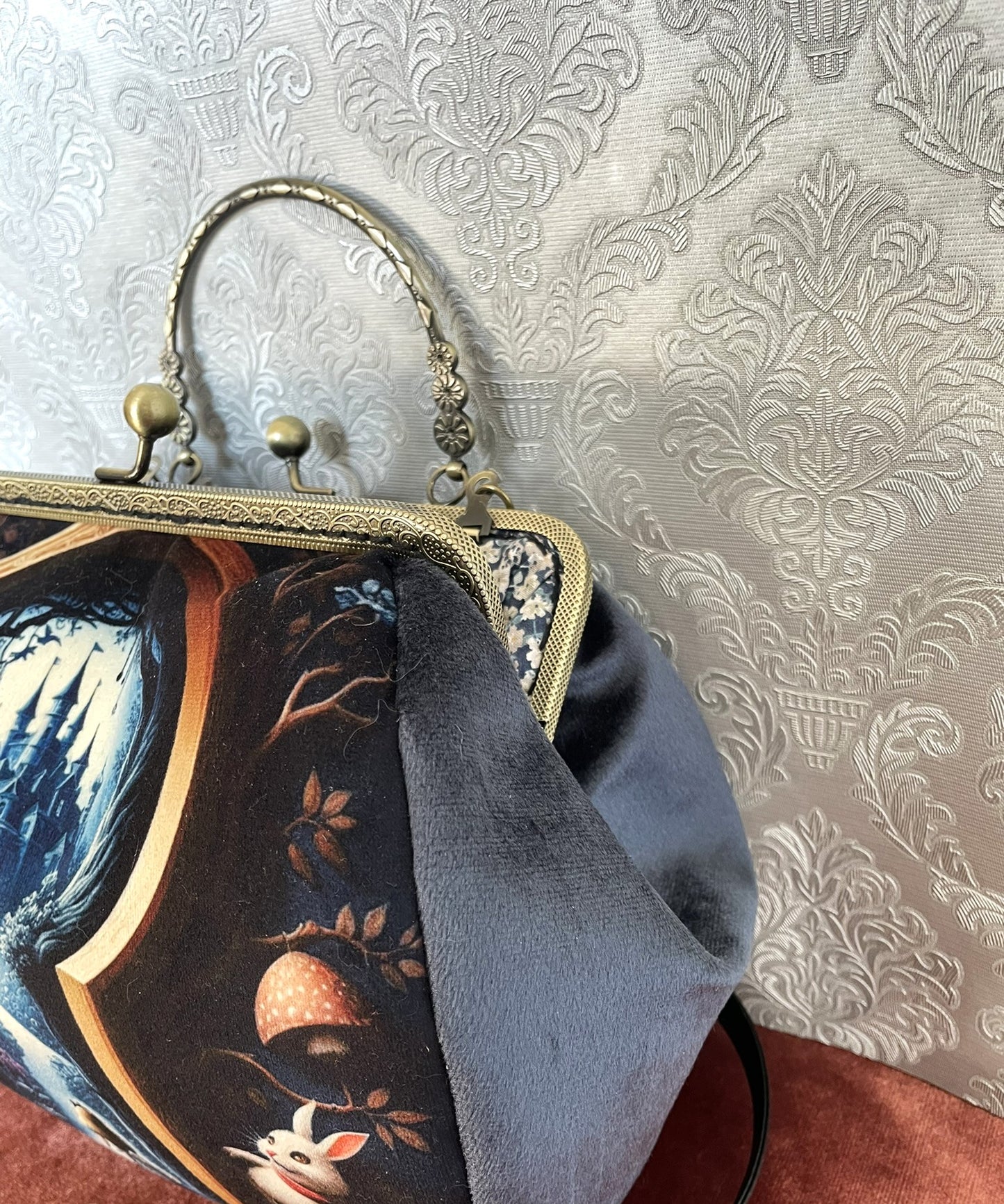 Gros plan sur le velours bleu soyeux et le fermoir bronze vieilli du sac Le Secret d'Alice.