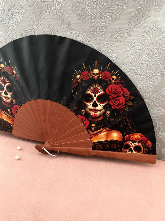 Détail de l'illustration et de la monture en bois vernis de l'éventail Catrina gothique aux détails dorés.