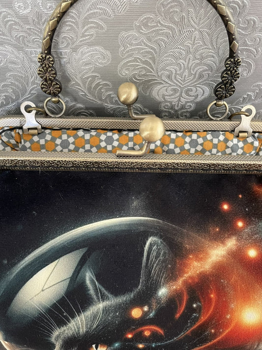 Zoom sur le fermoir cliquet en bronze ciselé et la doublure intérieure au motif géométrique rétro d'un sac sur le thème de l'espace.