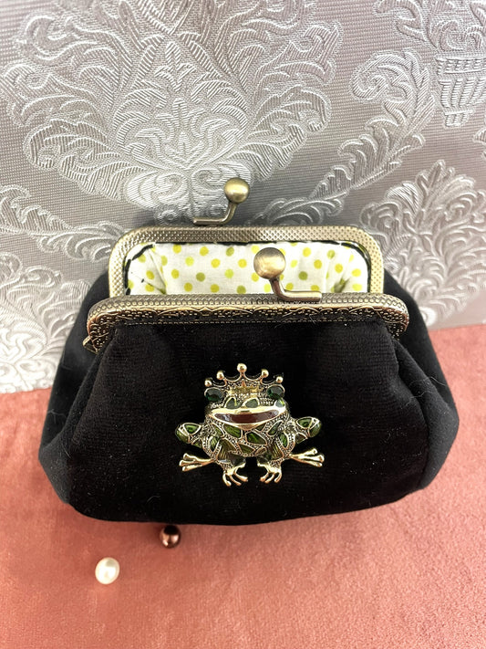 Vue de l'intérieur du porte-monnaie avec sa doublure blanche à pois vert anis et son armature métallique bronze.