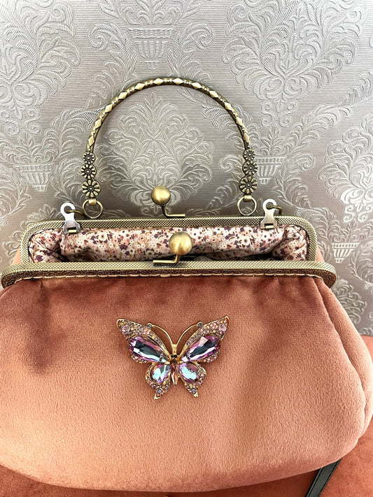 Intérieur du sac vieux rose ouvert révélant une doublure fleurie mauve et le détail du fermoir.