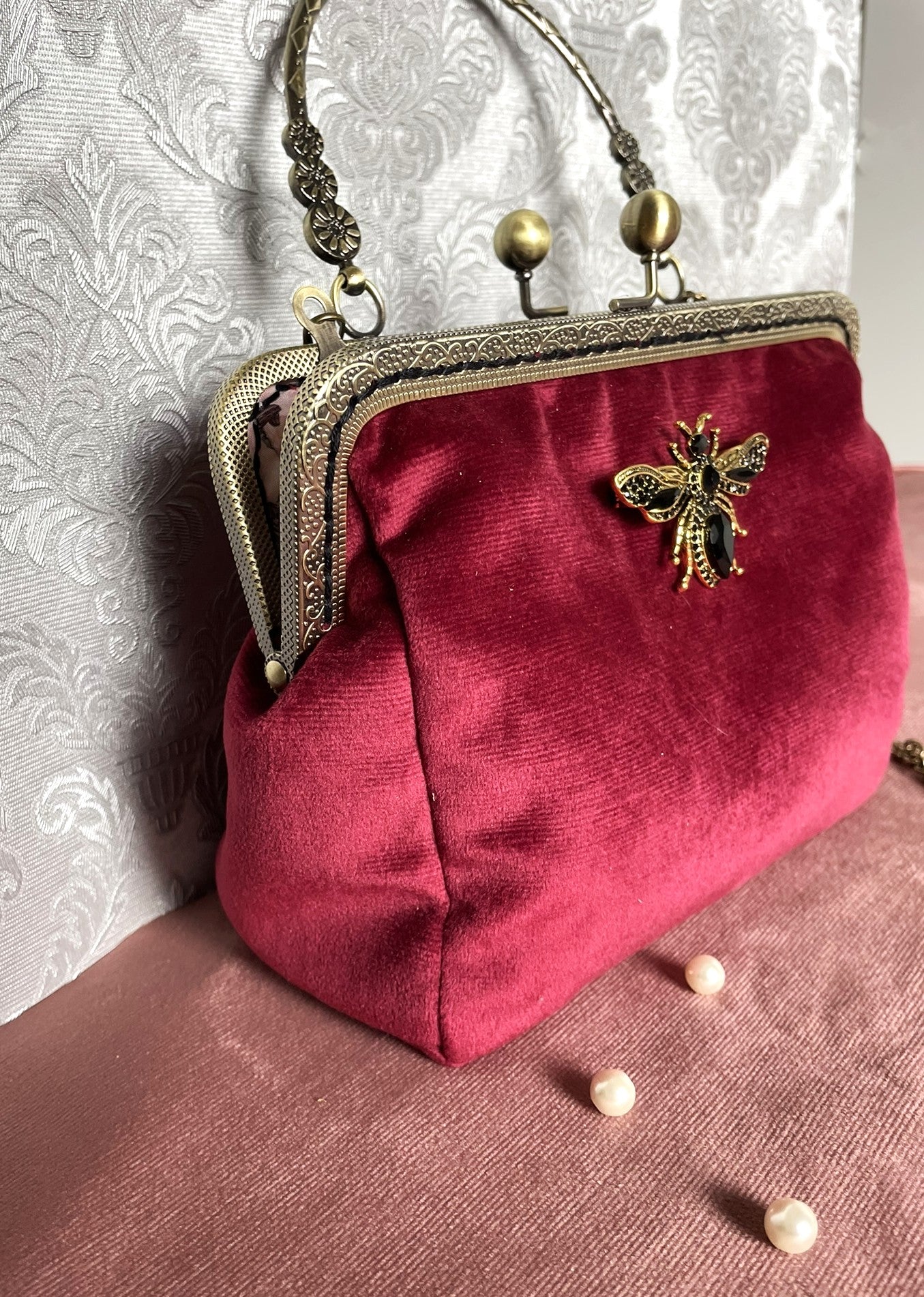 Détail du soufflet de profil en velours bordeaux et de la monture rétro métallique travaillée sur la pochette Le Comptoir de Suzanne.