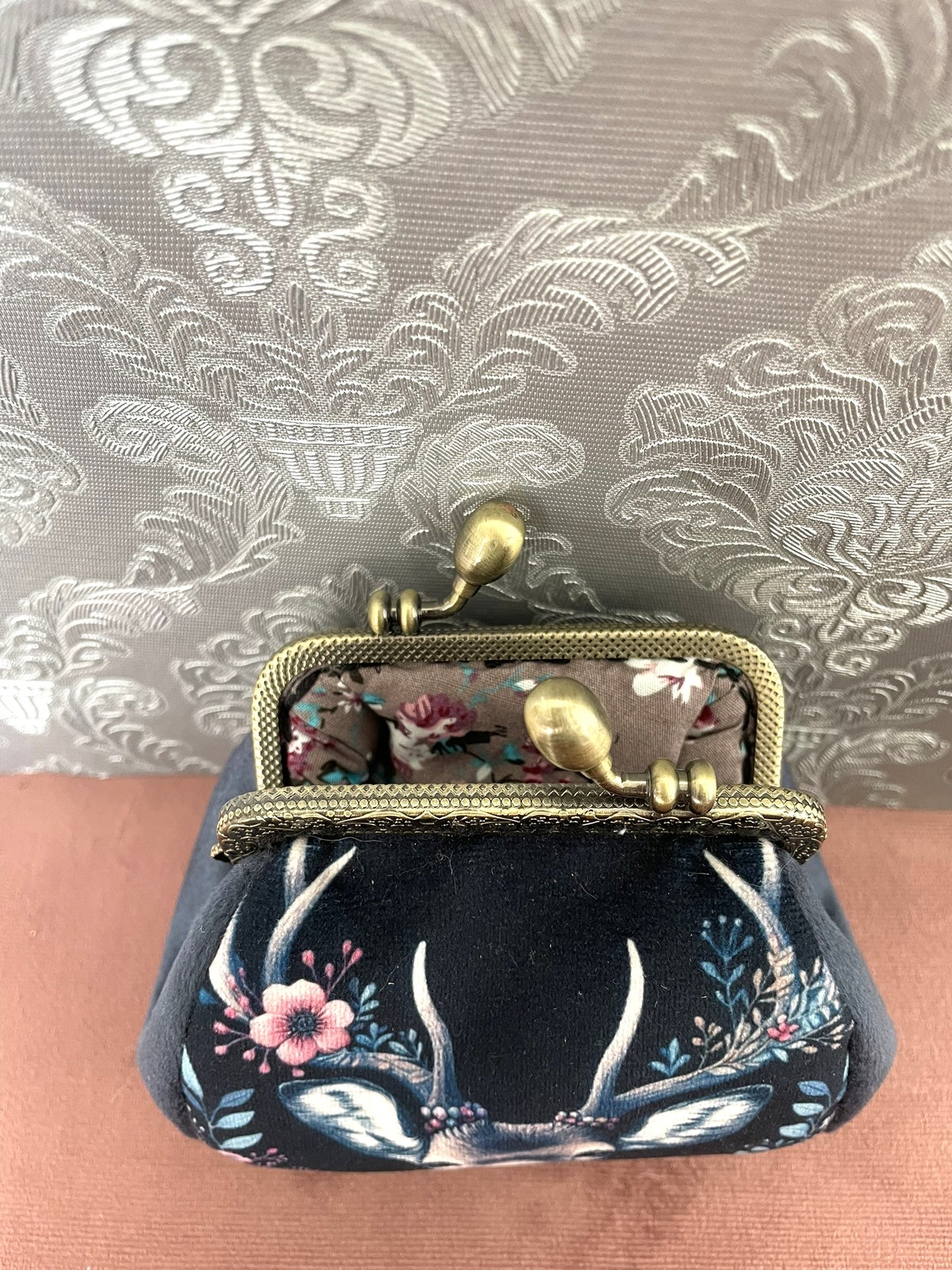 Intérieur ouvert d'un porte-monnaie rétro montrant une doublure en tissu imprimé de roses romantiques.