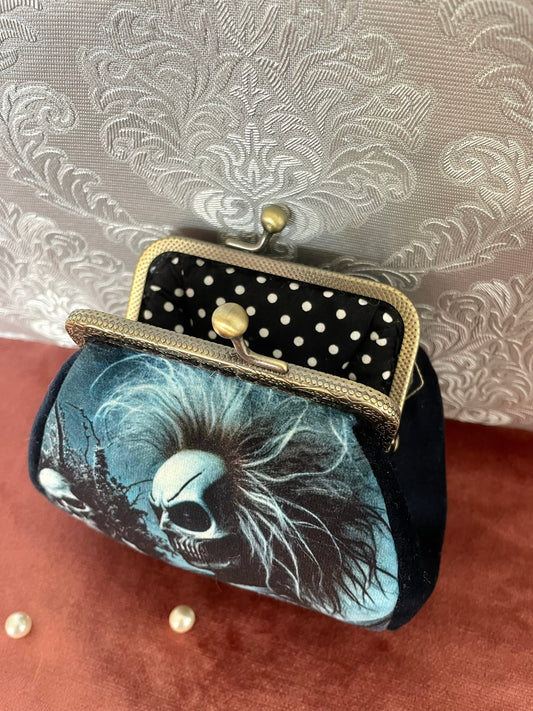 Vue ouverte du porte-monnaie squelette montrant la doublure noire à pois blancs et le fermoir vintage.