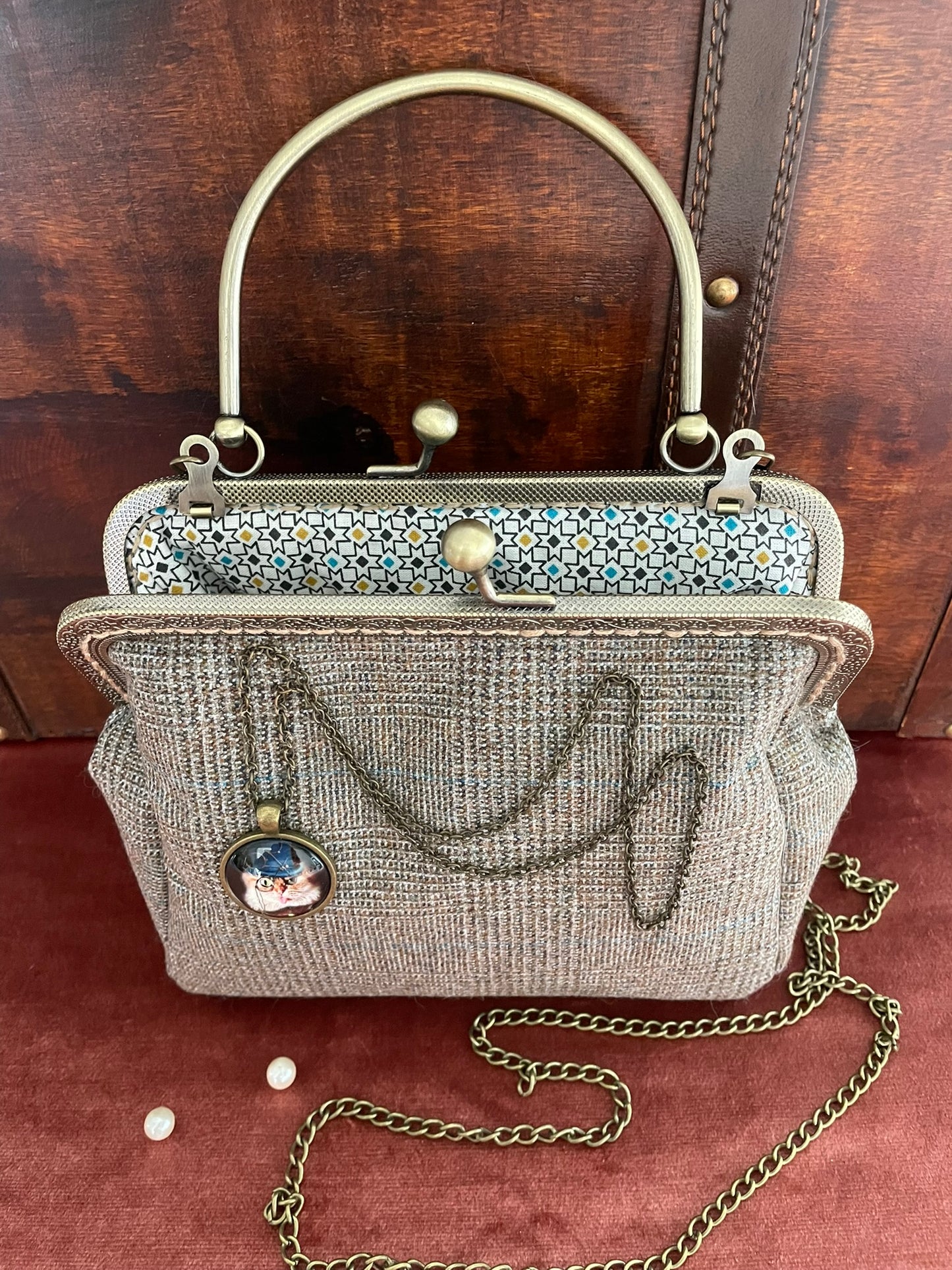 Sac de créateur porté main, textile tweed haut de gamme et finitions bronze vieilli.