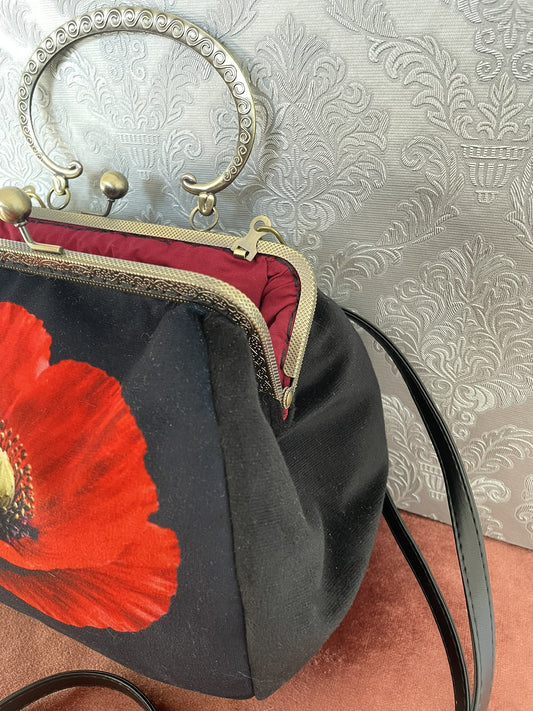 Vue de trois-quarts sac retro velours noir motif coquelicot rouge avec bandouliere noire