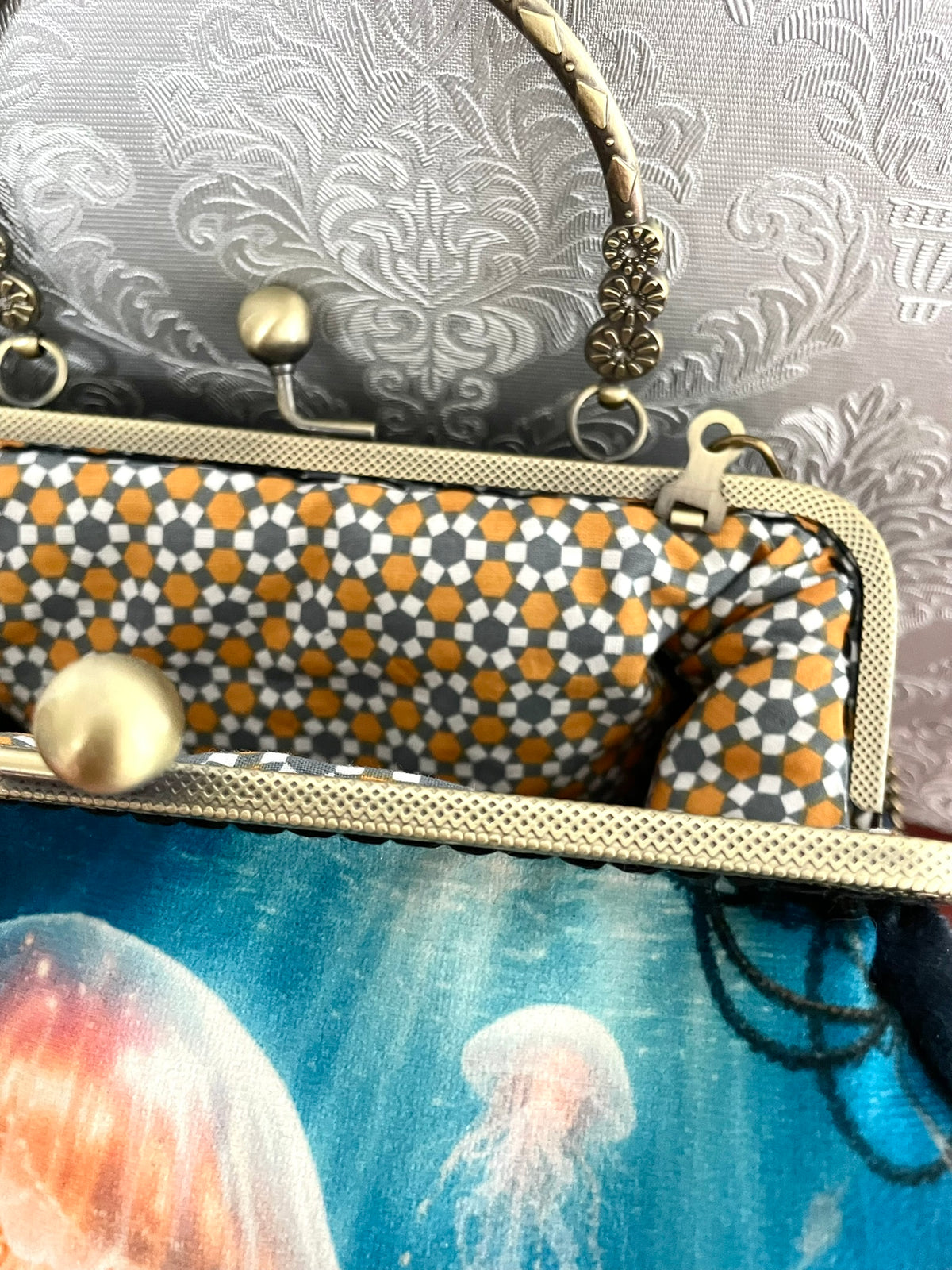 Vue de trois-quarts sac retro velours bleu nuit motif méduses lumineuses et fermoir effet bronze Le Comptoir de Suzanne