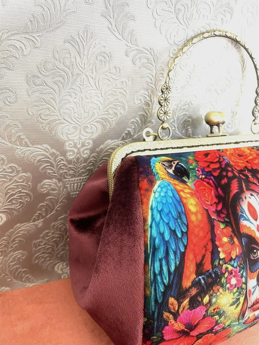 Sac rétro Calavera vu de trois-quarts montrant le velours vieux rose, l'armature effet bronze et le motif perroquet