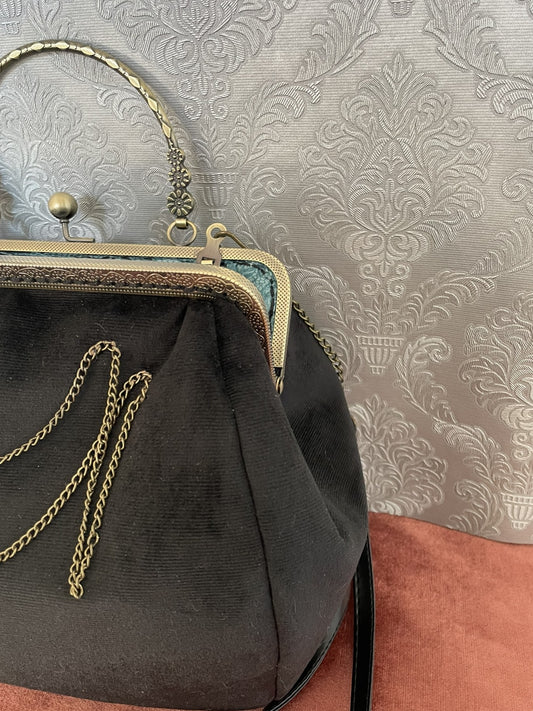Vue de profil du sac victorien noir montrant la texture du velours et le fermoir ciselé.