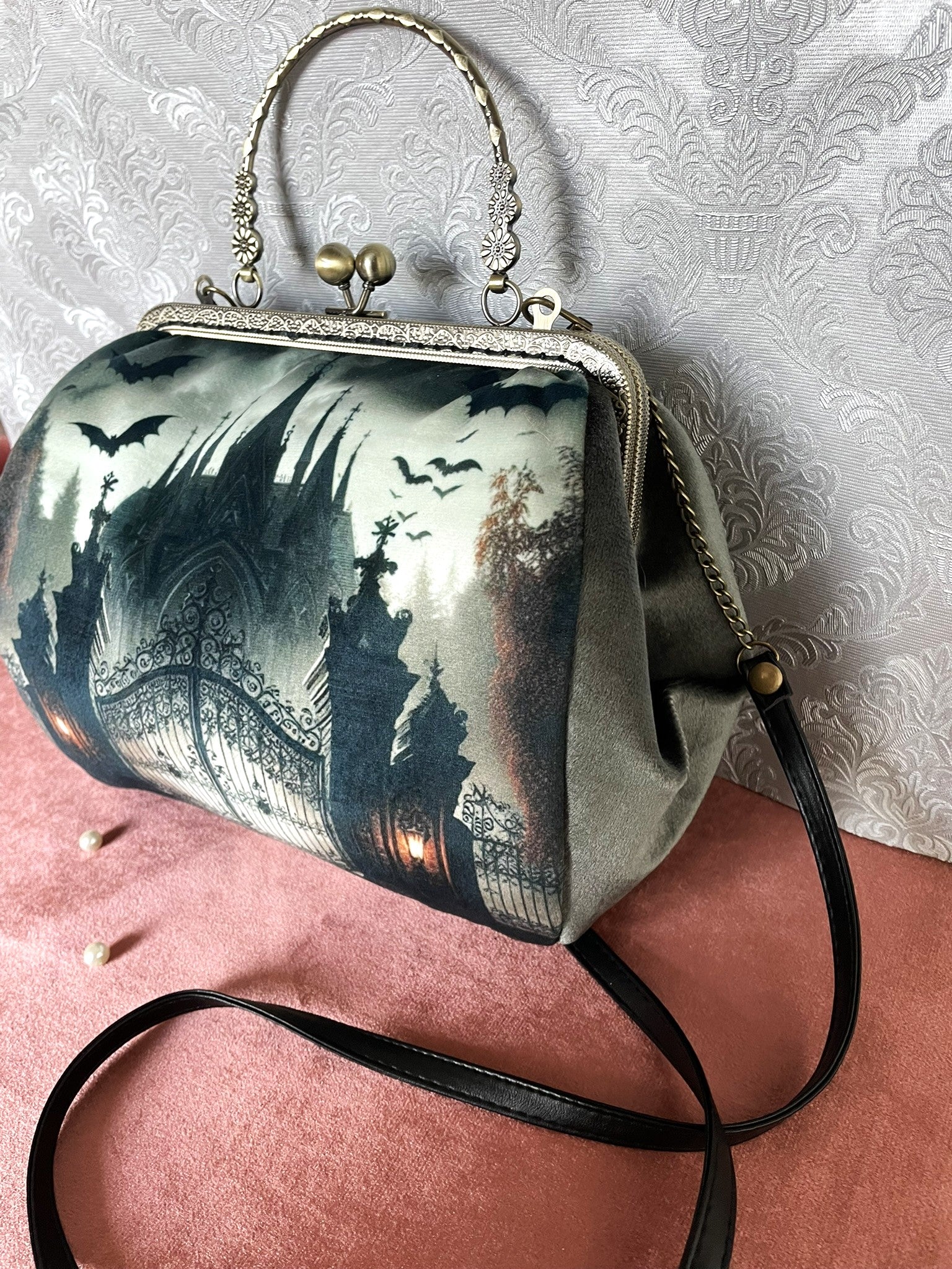 Sac Manoir Hanté posé sur un décor velours rose avec perles, style esthétique Dark Academia.