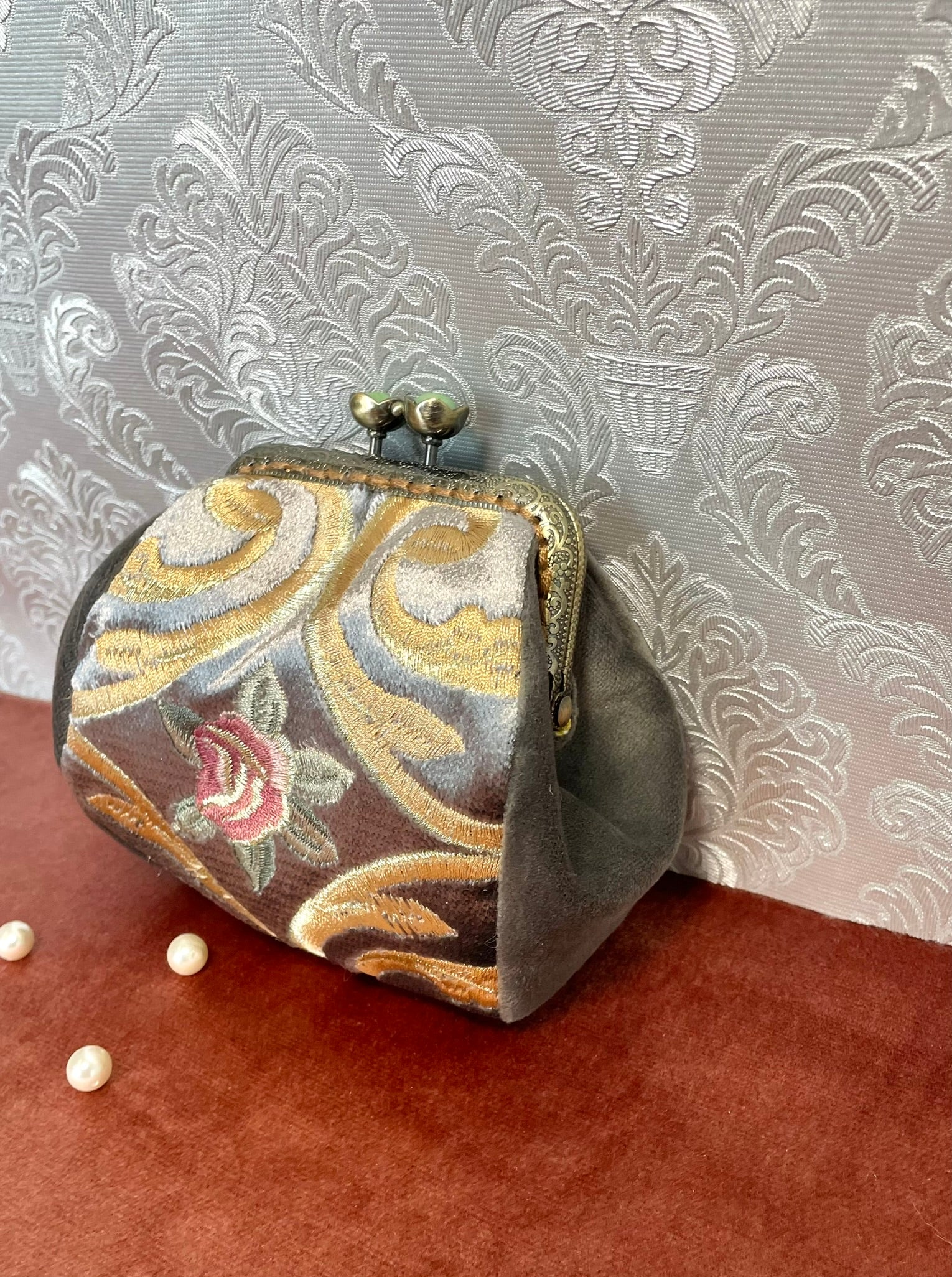 Gros plan sur le relief de la broderie et la douceur du velours gris.