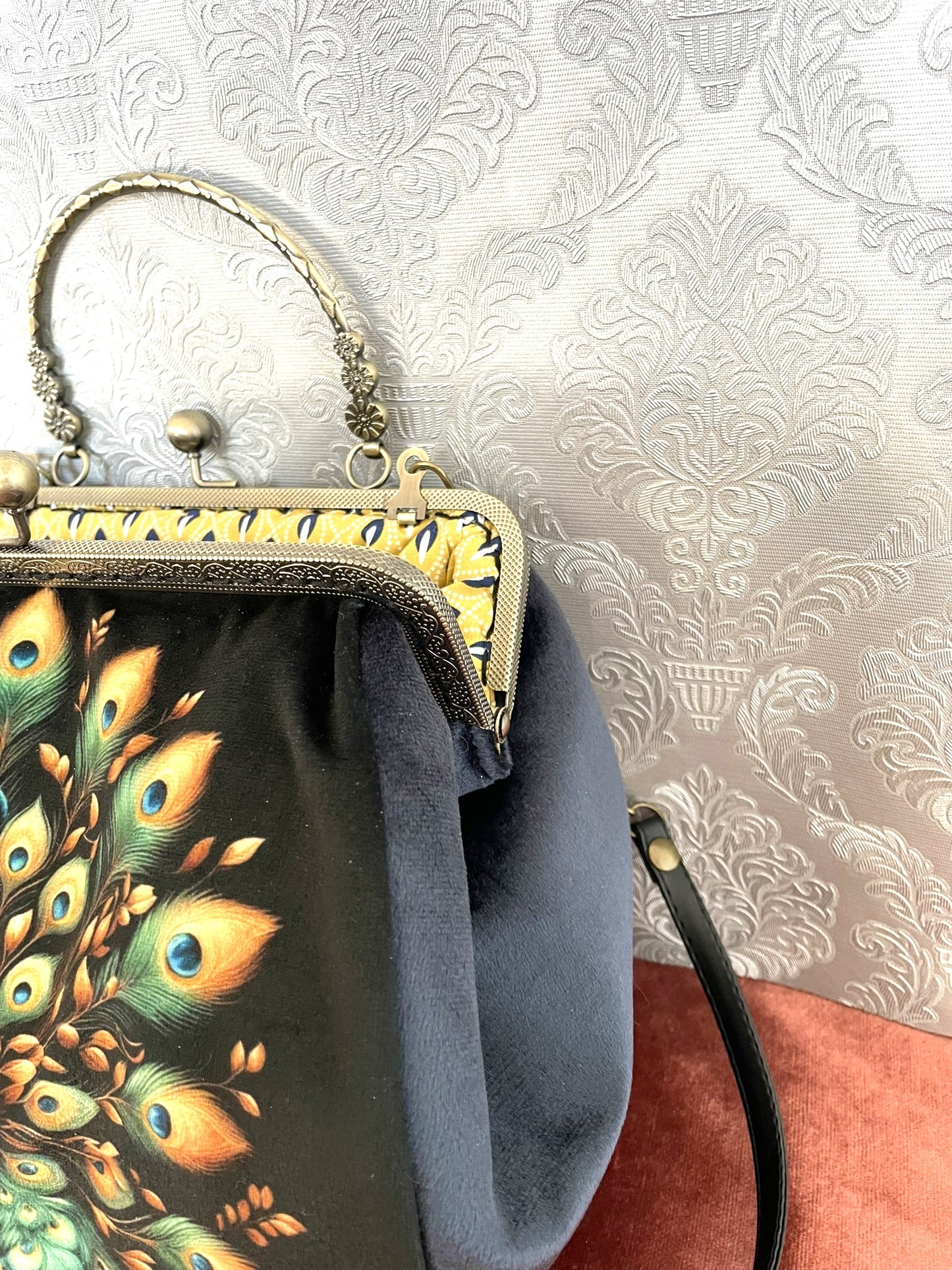 Gros plan sur le fermoir en bronze travaillé et le velours bleu nuit du sac La Plume Impériale.