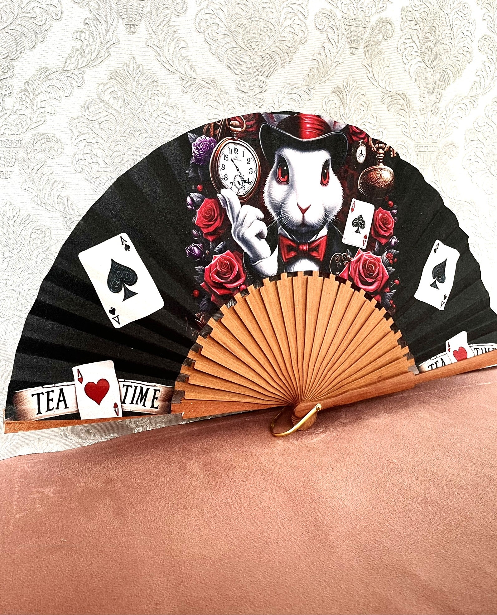 Détail du tissu exclusif d'un éventail en bois montrant le Lapin Blanc élégant, des As de Pique, des As de Cœur et la mention Tea Time.