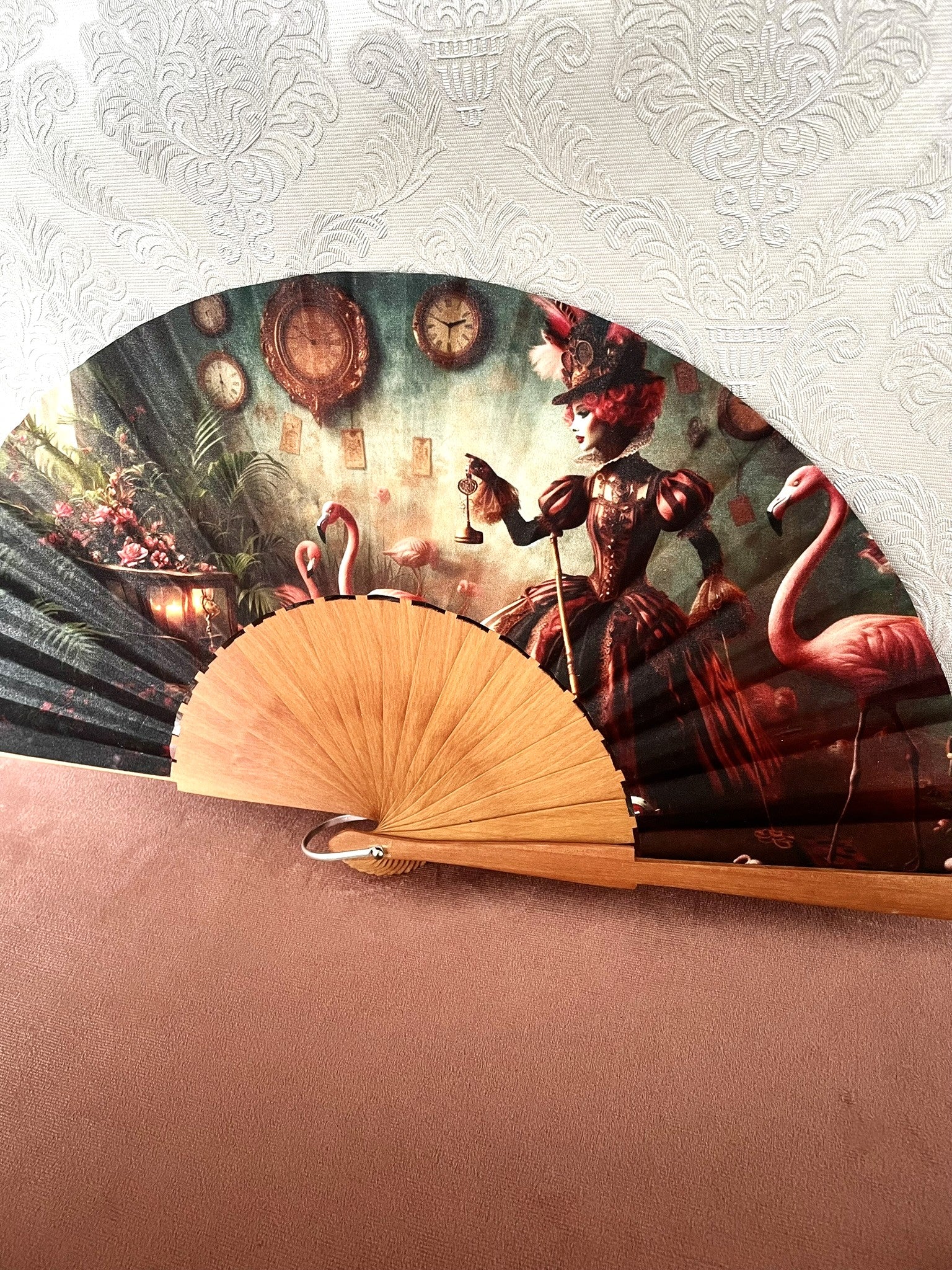 Détail du tissu exclusif d'un éventail en bois montrant une femme élégante en tenue baroque steampunk avec une clé, des horloges anciennes et des flamants roses.