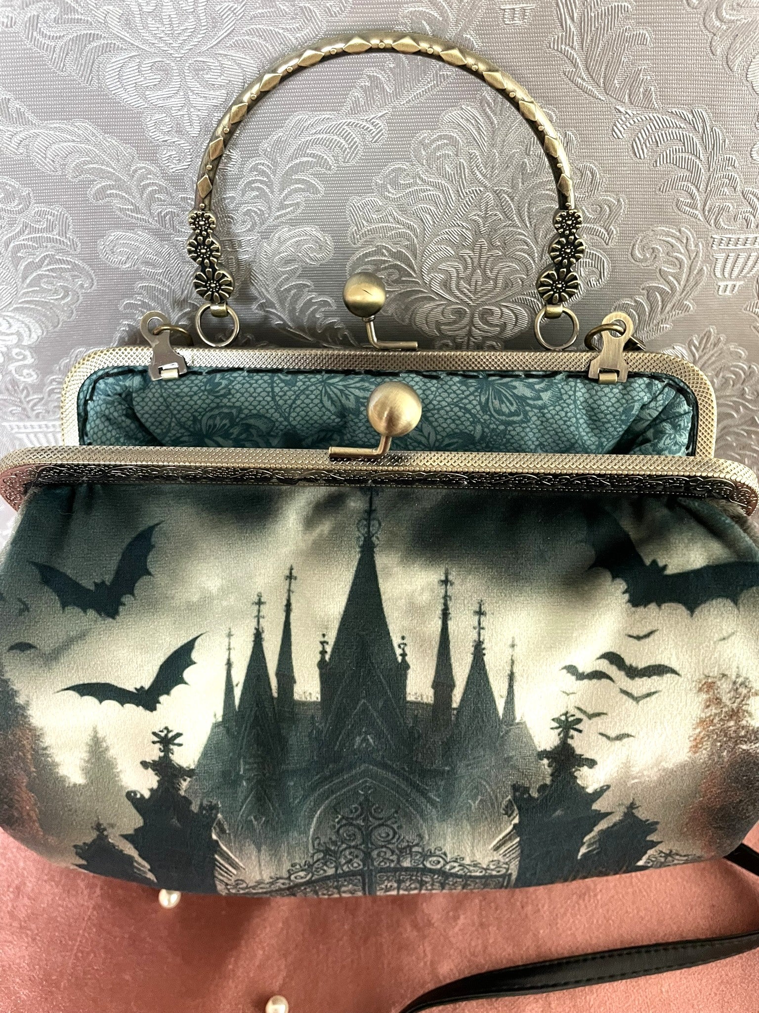 Vue de l'intérieur du sac montrant la doublure verte à motifs baroques et l'espace de rangement.