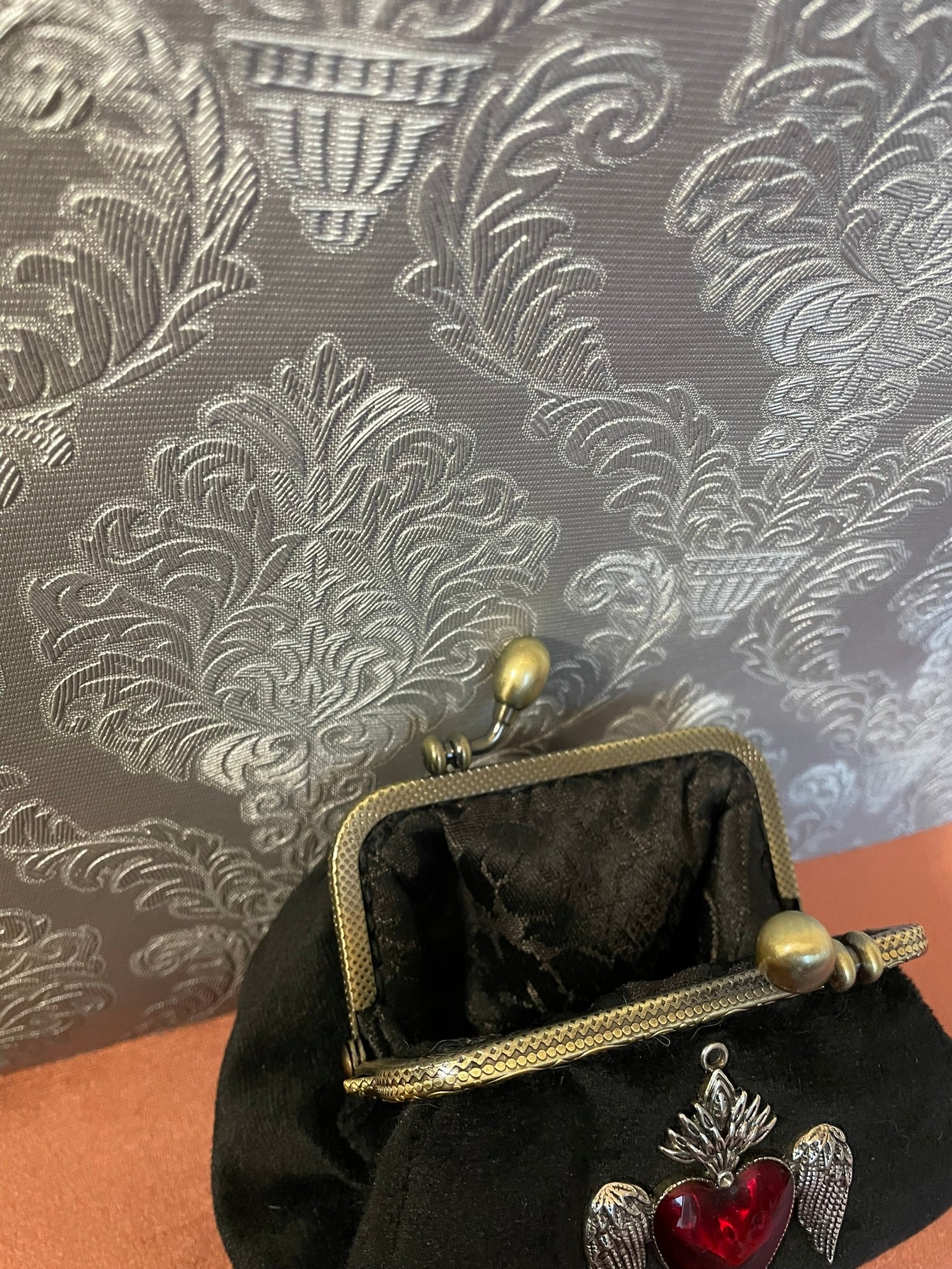 Intérieur du porte-monnaie avec doublure baroque satinée noire à motifs ton sur ton.