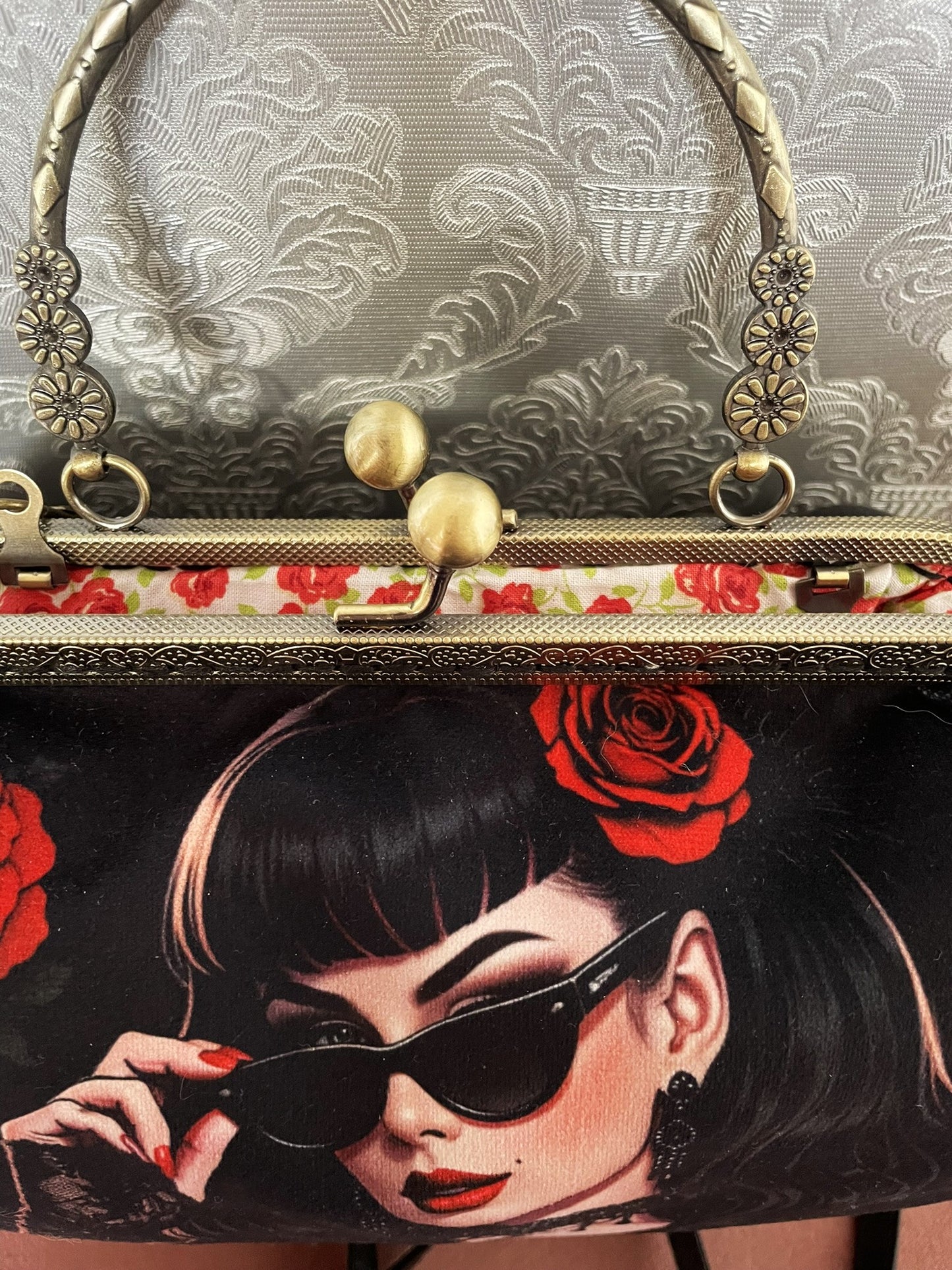 Zoom sur le portrait d'une pin-up gothique avec lunettes de soleil, rose rouge et doublure intérieure fleurie.