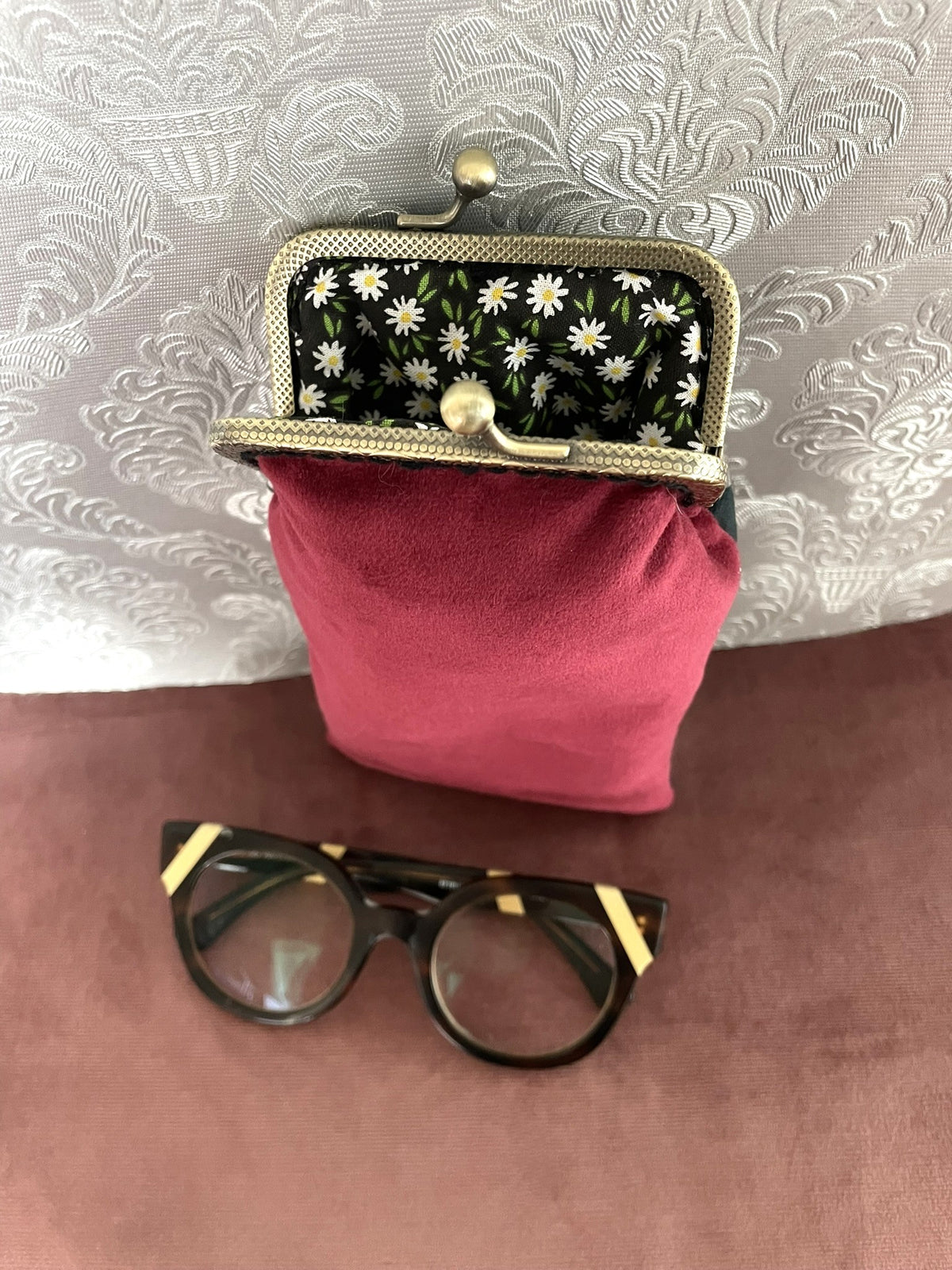 Ouverture de l'étui à lunettes dévoilant le velours rouge et la doublure noire à pâquerettes