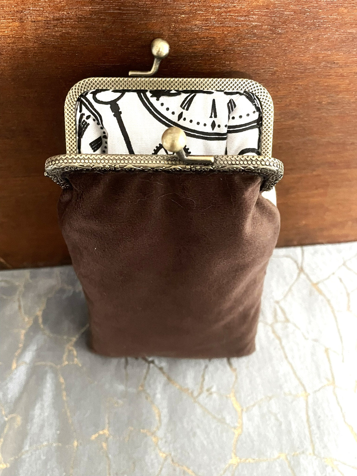Vue de l'ouverture de l'étui à lunettes rétro montrant le dos en velours marron chocolat et la doublure horloges noires