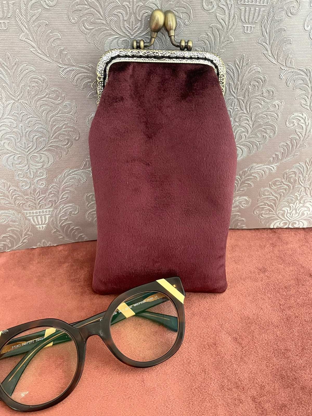 Dos en velours bordeaux d'un etui a lunettes retro a fermoir clic-clac bronze