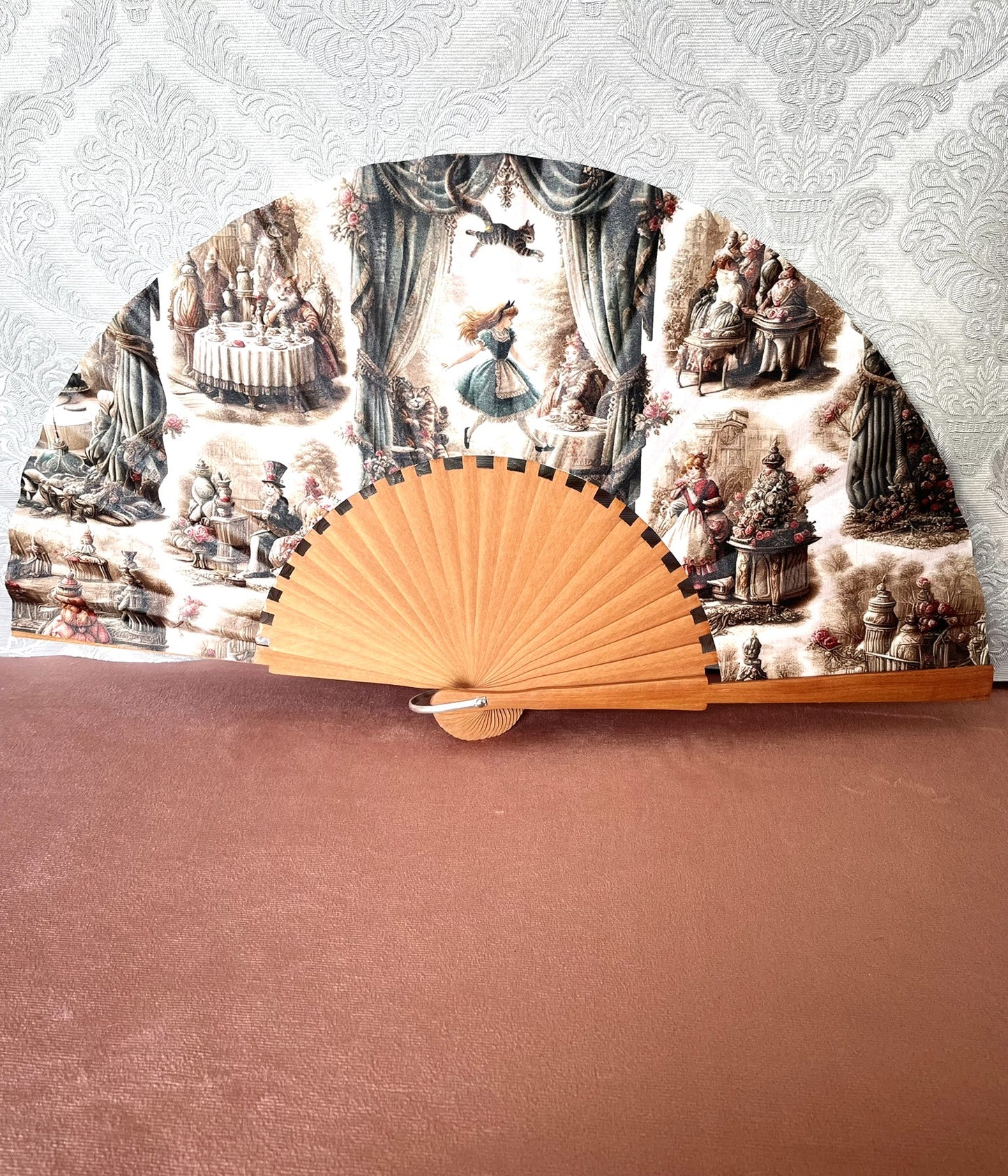 Éventail artisanal ouvert Le Comptoir de Suzanne en bois avec tissu exclusif représentant Alice au Pays des Merveilles façon gravure vintage.