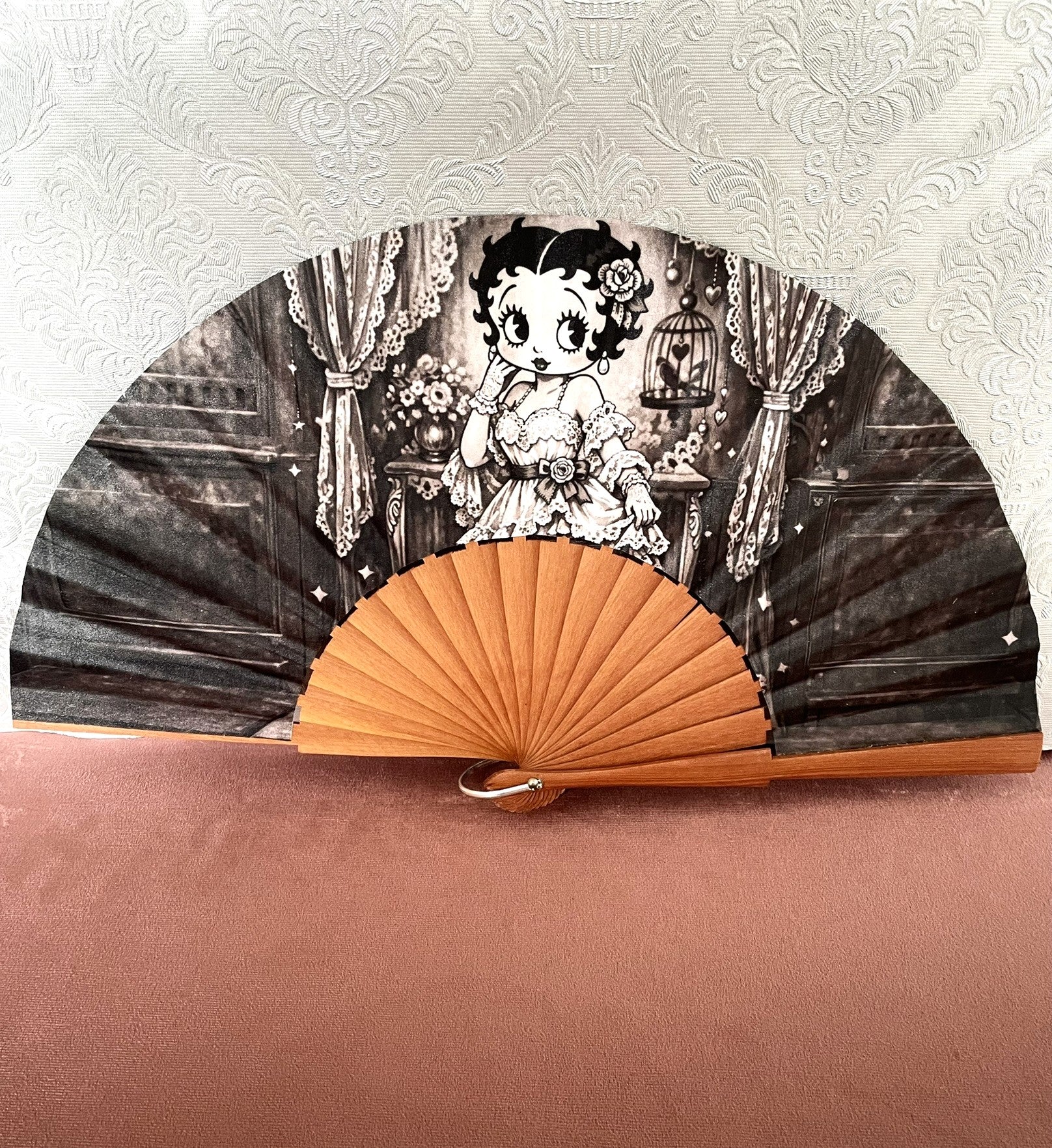 Éventail artisanal ouvert Le Comptoir de Suzanne en bois avec tissu exclusif représentant Betty Boop en robe dentelle dans un boudoir rétro noir et blanc.