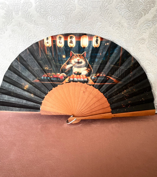 Éventail artisanal ouvert Le Comptoir de Suzanne en bois avec tissu exclusif représentant un chat rondouillard dégustant des sushis sous des lanternes japonaises.