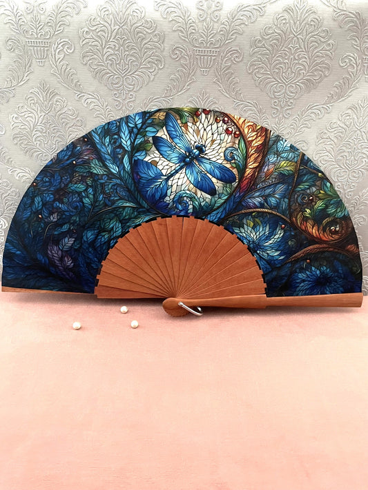 Éventail artisanal ouvert Le Comptoir de Suzanne en bois de fruitier avec tissu exclusif motif libellule bleue style vitrail.