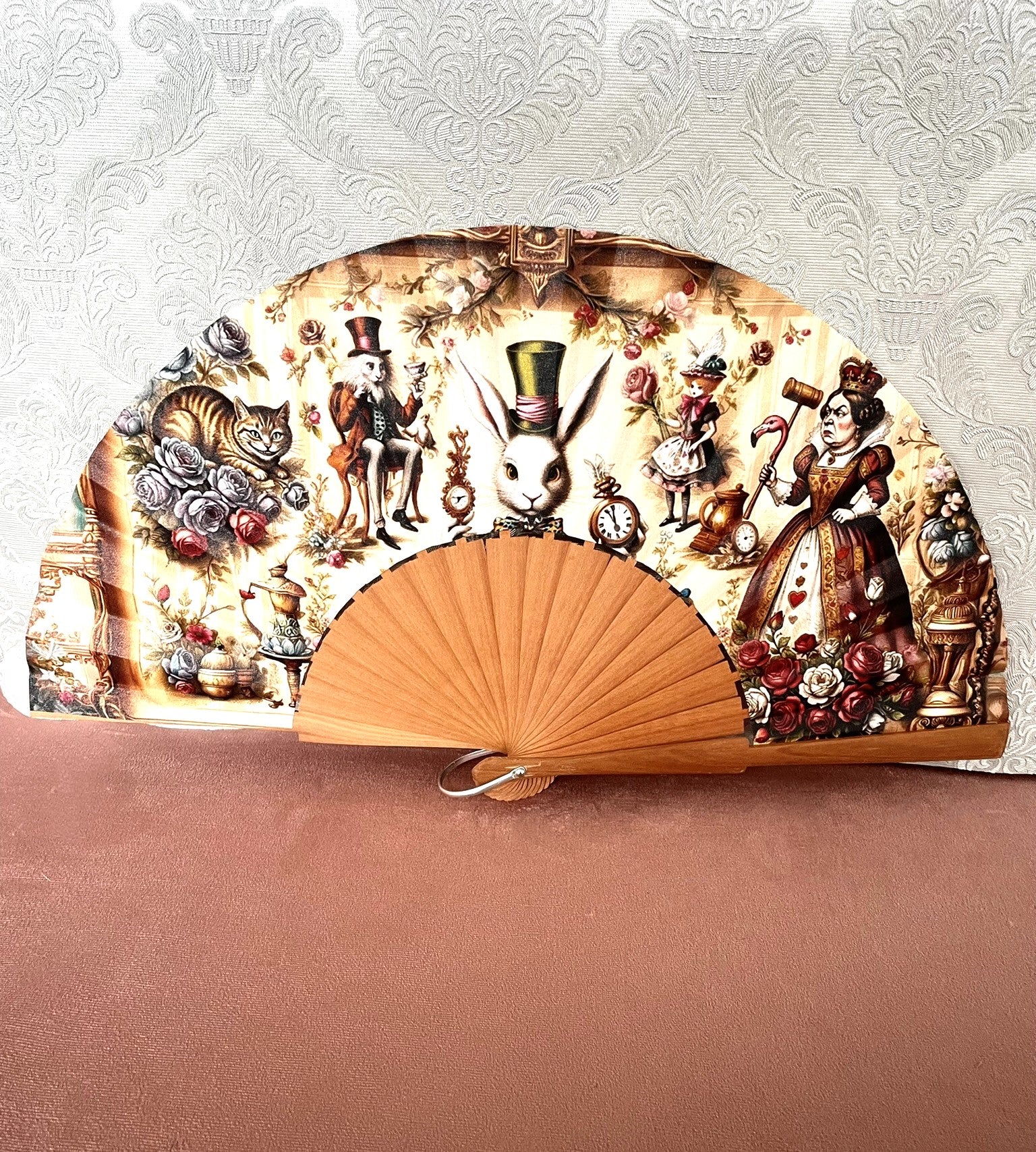 Éventail artisanal ouvert Le Comptoir de Suzanne en bois avec tissu exclusif représentant une scène vintage réunissant les personnages d'Alice au Pays des Merveilles.