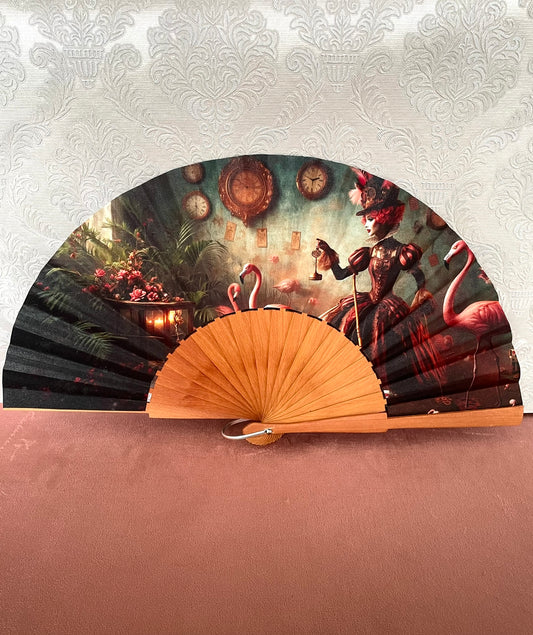 Éventail artisanal ouvert Le Comptoir de Suzanne en bois avec tissu exclusif représentant la Reine de Cœur entourée de flamants roses et d'horloges vintage.