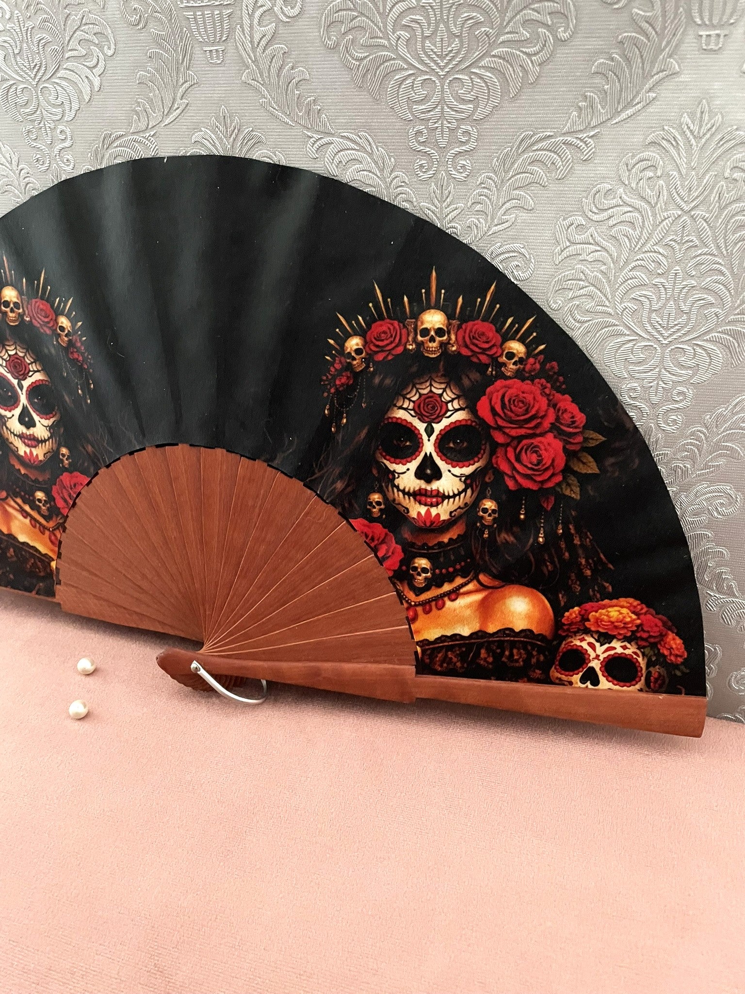 Détail de l'illustration et de la monture en bois vernis de l'éventail Catrina gothique aux détails dorés.