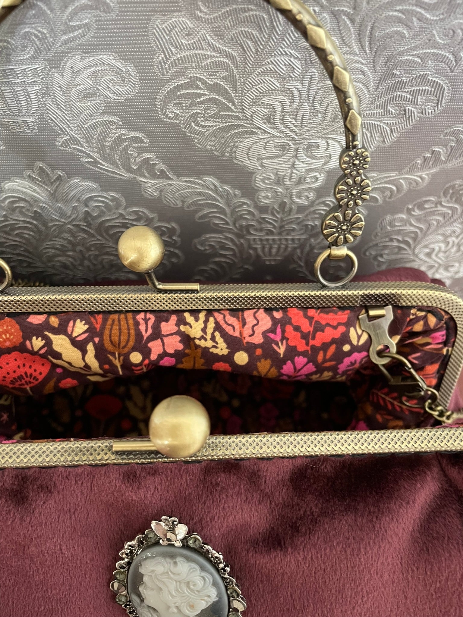 Zoom sur le fermoir cliquet en bronze ciselé et la doublure intérieure imprimé floral automnal du sac camée.