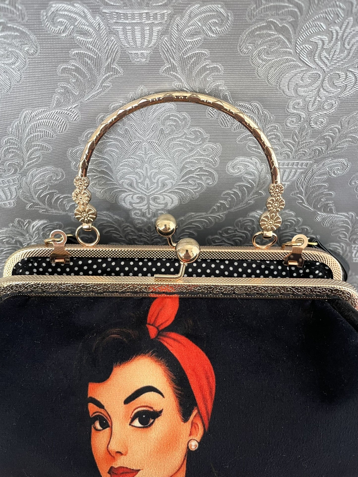 Zoom sur le fermoir cliquet en bronze doré ciselé et la doublure intérieure à pois noirs et blancs de style rétro pin-up.