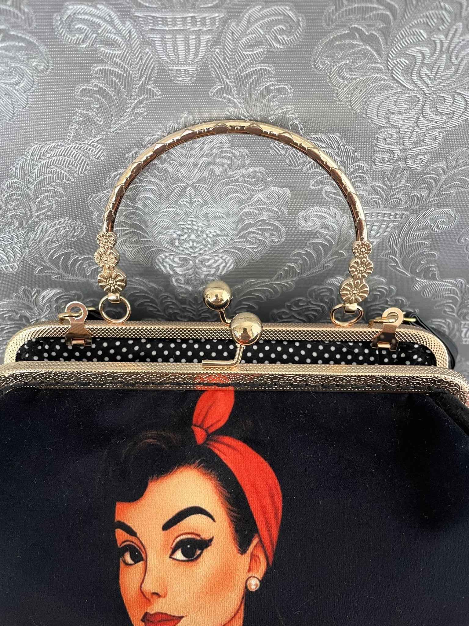Zoom sur le fermoir cliquet en bronze doré ciselé et la doublure intérieure à pois noirs et blancs de style rétro pin-up.
