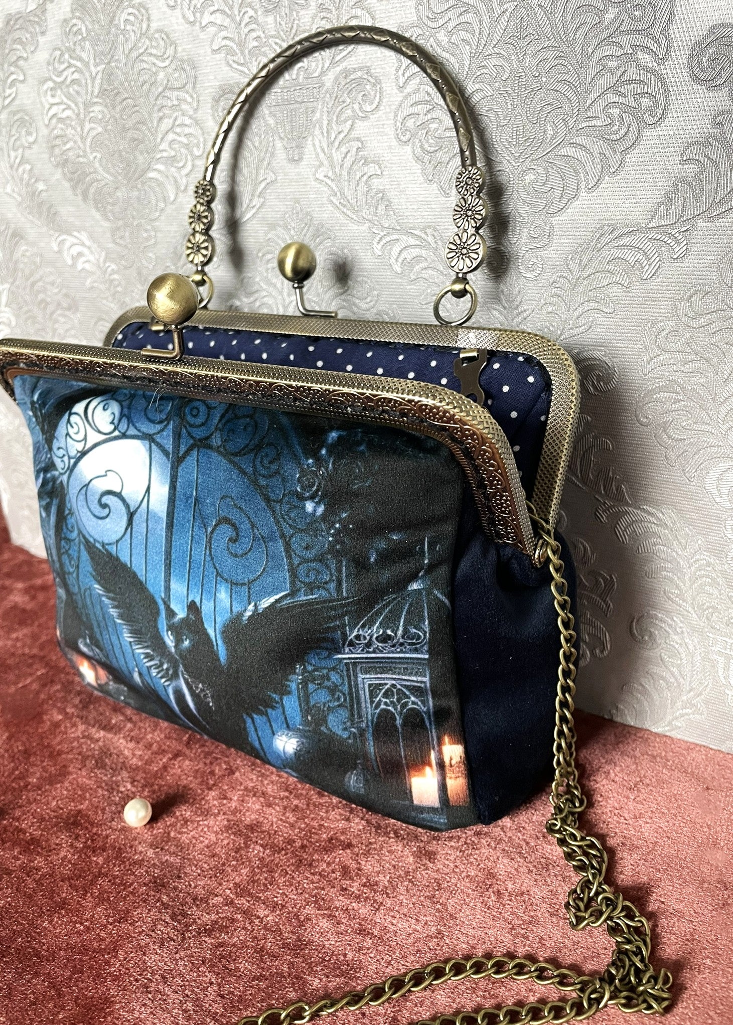 Côté du sac en velours bleu nuit soyeux, fermoir baiser travaillé et poignée rigide effet bronze.