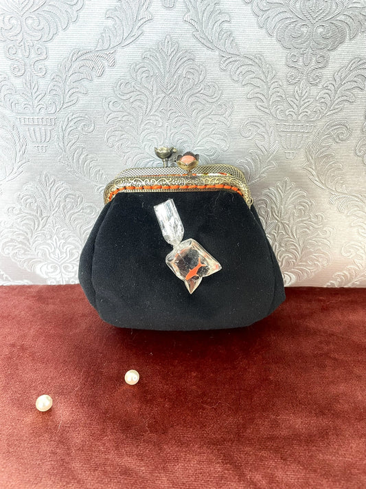 Porte-monnaie artisanal avec illustration d'un poisson rouge dans son sac de transport transparent, côtés en velours noir.