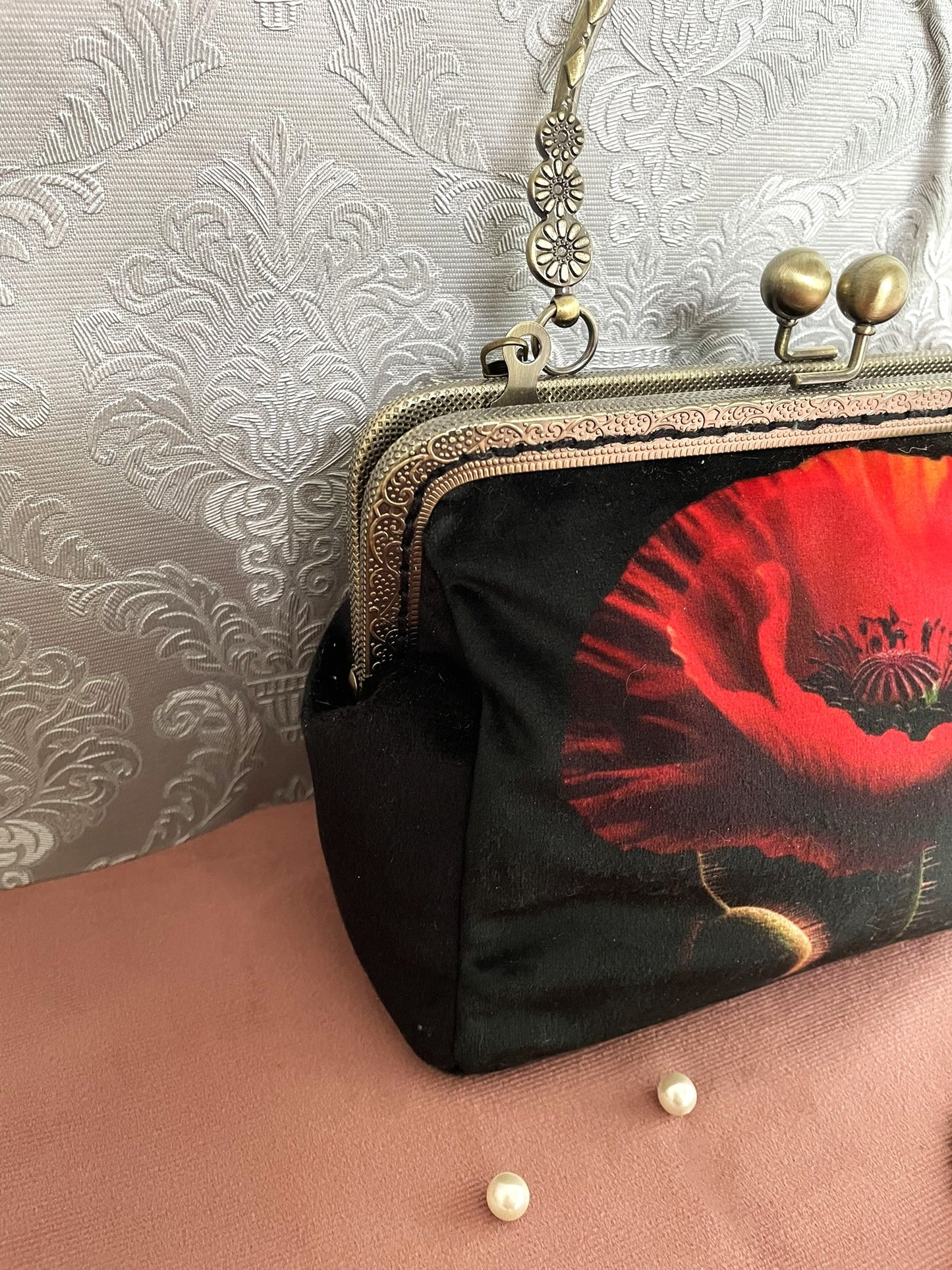 Zoom de profil sur le soufflet en velours lisse noir soyeux et la monture rétro métallique bronze ciselée de la pochette Le Comptoir de Suzanne.