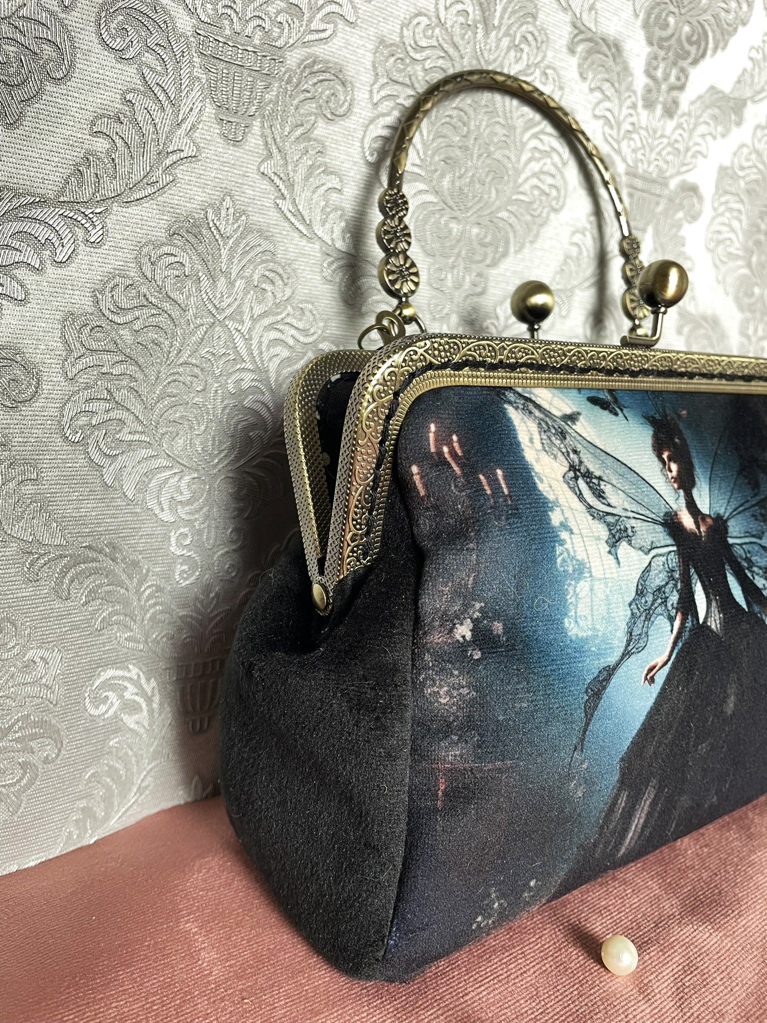 Zoom sur le soufflet de profil en velours noir soyeux et la monture métallique bronze gravée de la pochette fée Le Comptoir de Suzanne.