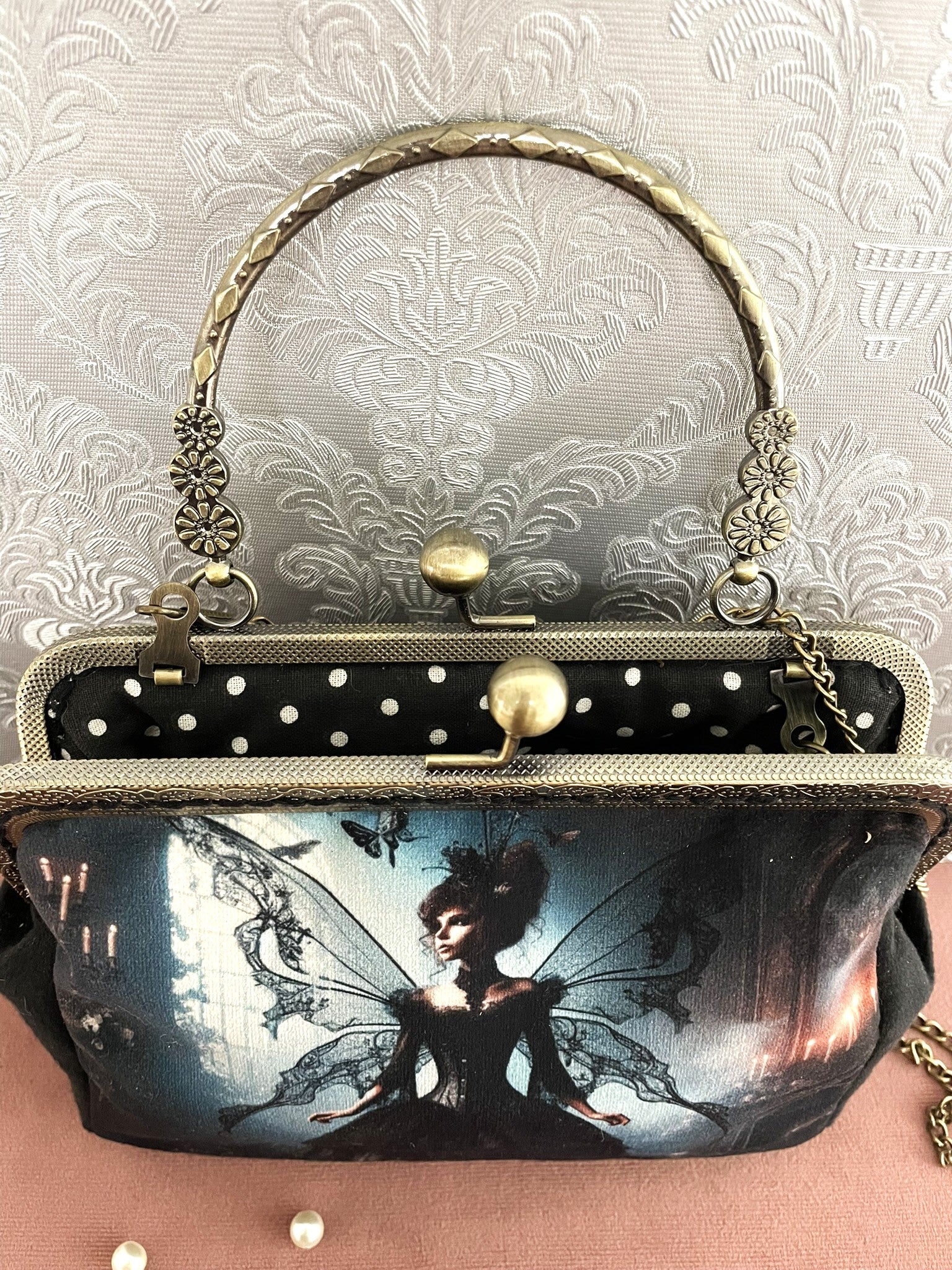 Vue du dessus de la pochette fée gothique ouverte révélant le fermoir esprit vintage et sa doublure intérieure noire à petits pois blancs.