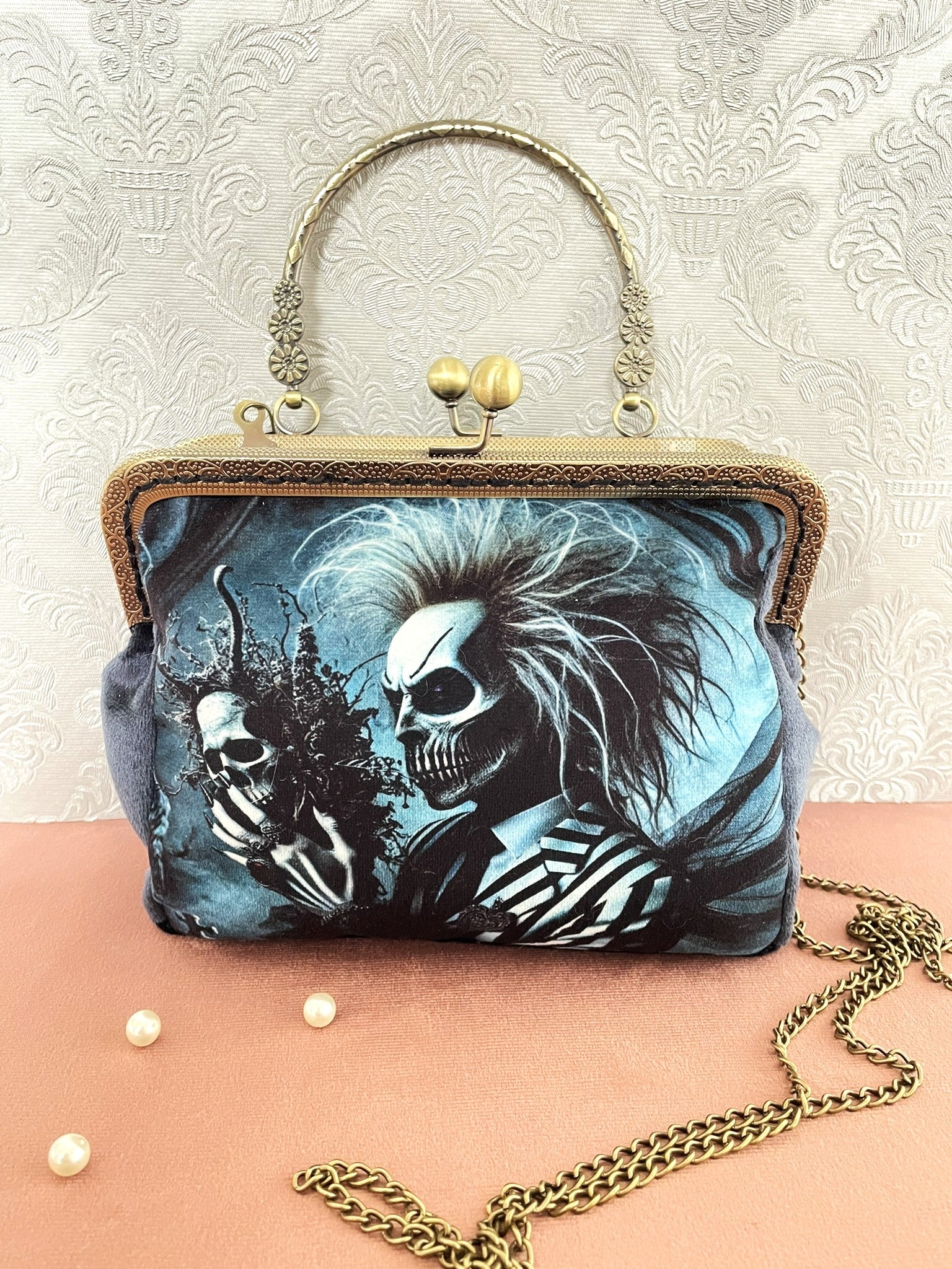Vue de face de la pochette clutch gothique en velours bleu représentant un personnage squelette au costume rayé fantastique avec sa chaîne amovible.
