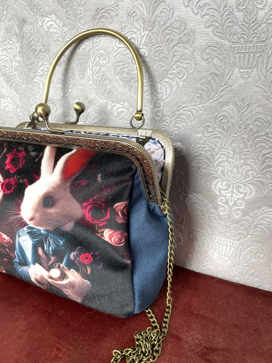 Sac rétro avec lapin élégant en habit bleu, décor floral et horloge.
