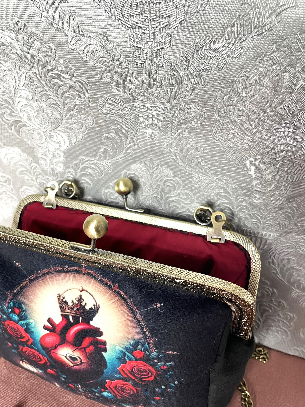 Vue du fermoir ouvert de couleur bronze antique et de la doublure rouge de la pochette cœur sacré Le Comptoir de Suzanne