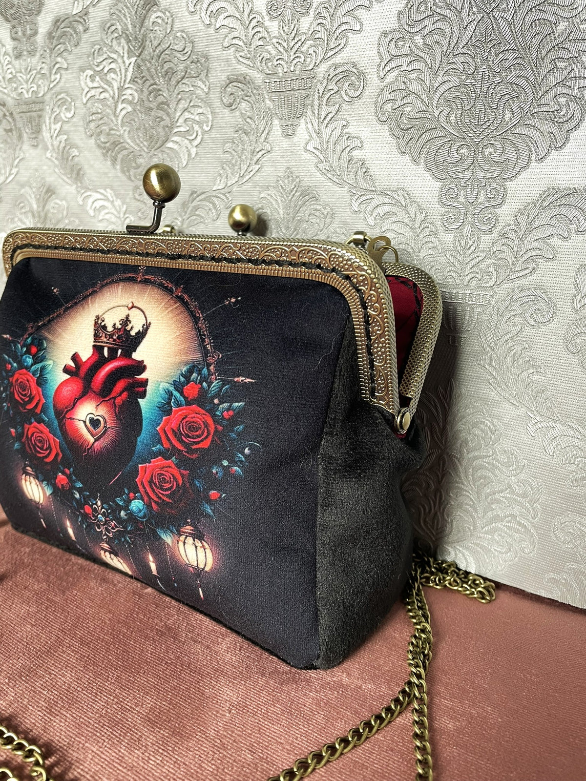 Vue de trois-quarts pochette rétro velours noir à fermoir de couleur bronze motif cœur sacré couronné Le Comptoir de Suzanne