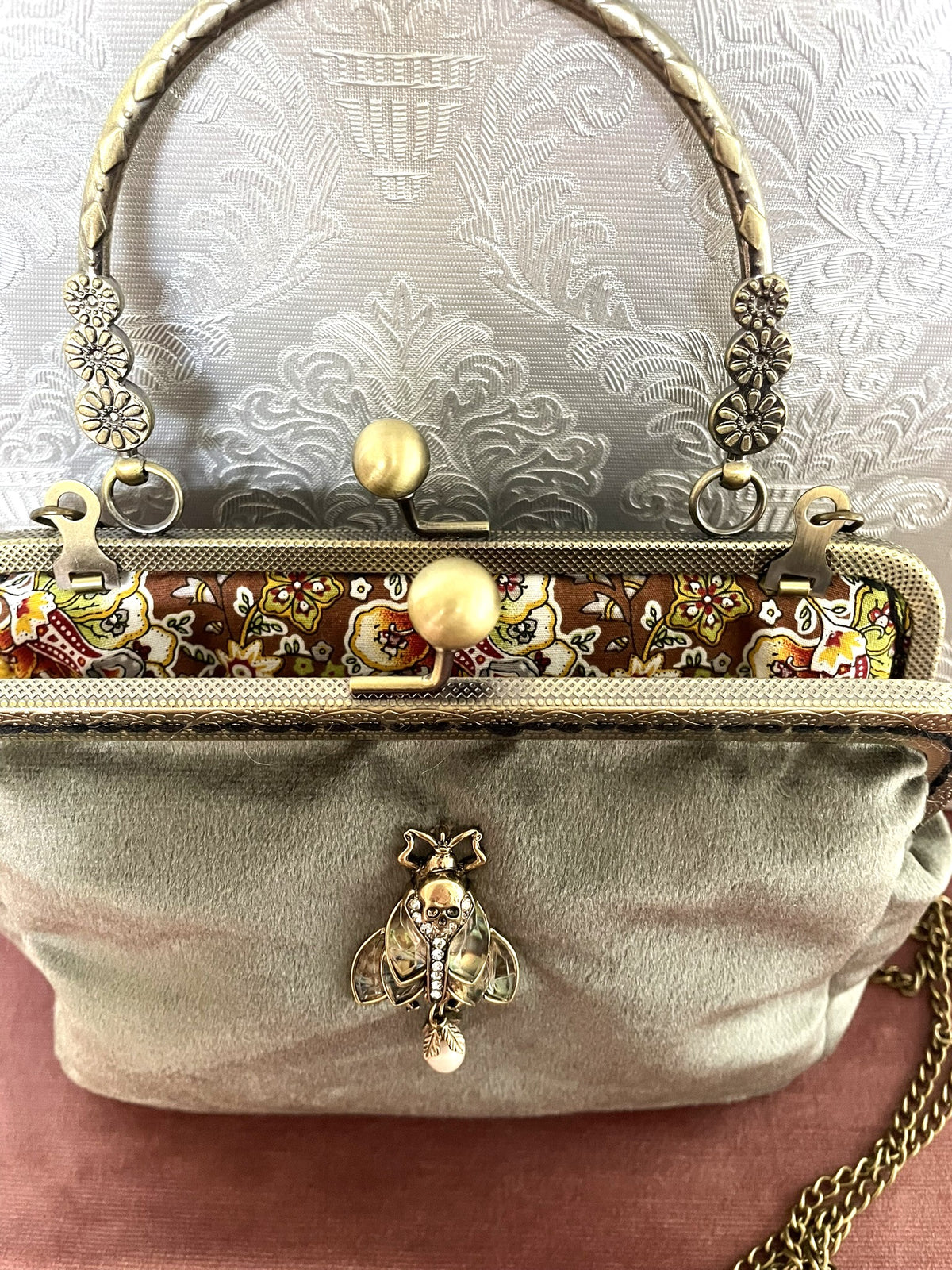 Vue rapprochée du fermoir ouvert couleur bronze et doublure fleurie ocre pochette vert sauge Le Comptoir de Suzanne