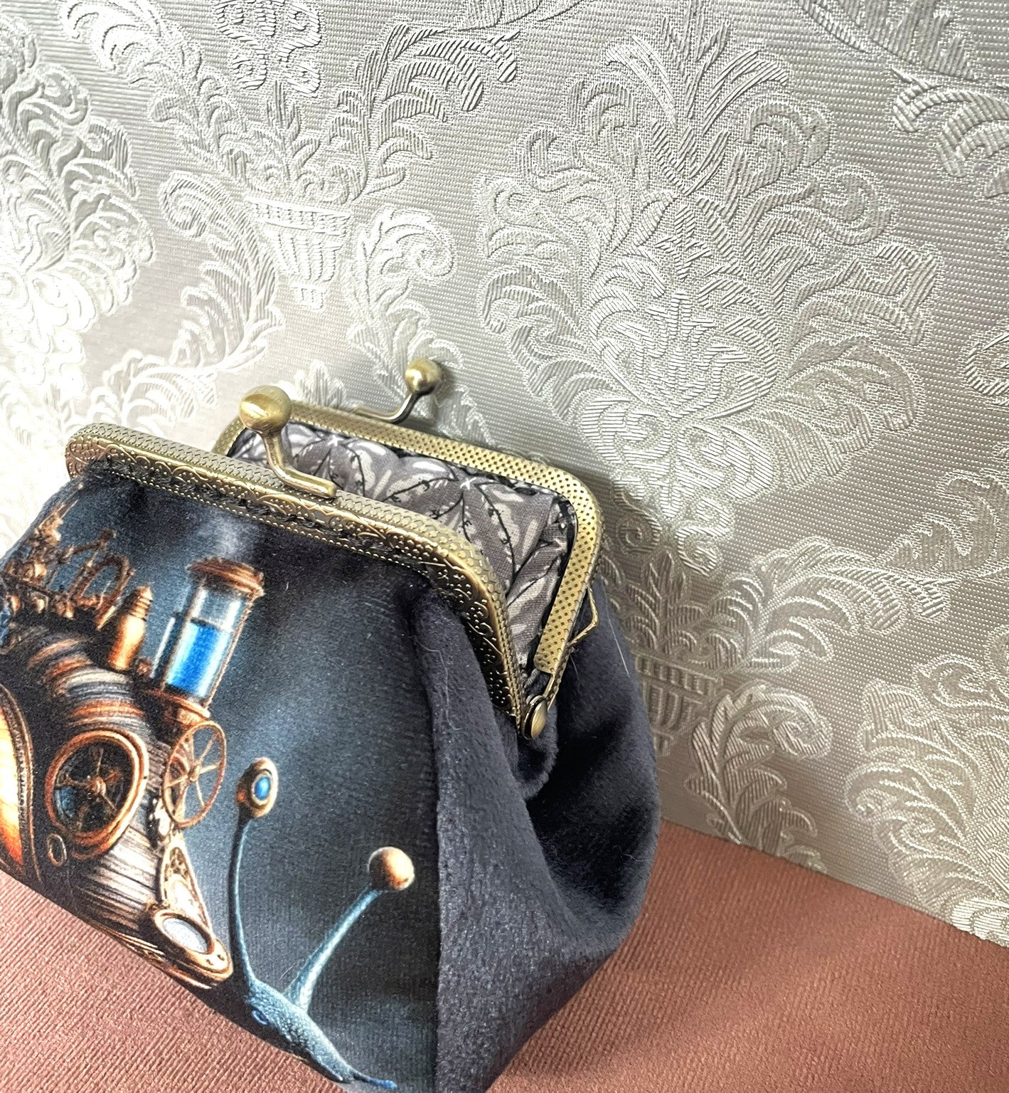 "Détail d'un porte-monnaie rétro à motif escargot steampunk avec fermoir bronze antique et doublure grise.
